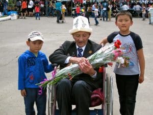 Kyrgyz children gifting flowers to an elderly veteran.
